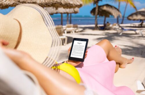 woman reading eBook on a beach; how to write a beach read