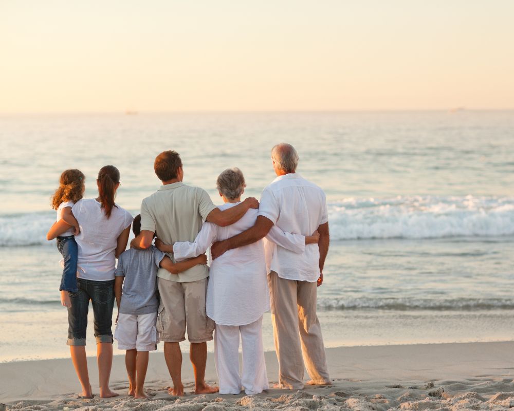 A multi-generational family standing on a beach facing the ocean; how to write a book about your life